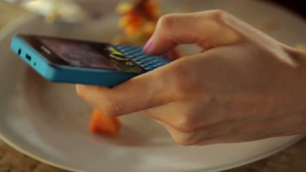 Женщина пишет смс на смартфоне и ест — стоковое видео