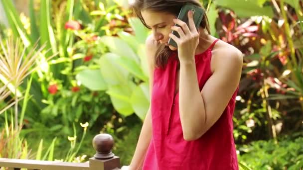 Vrouw praten over cellphone in tuin — Stockvideo