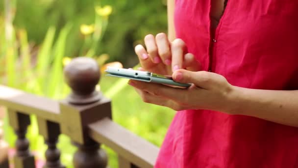 Frau schreibt SMS auf Smartphone im Garten — Stockvideo
