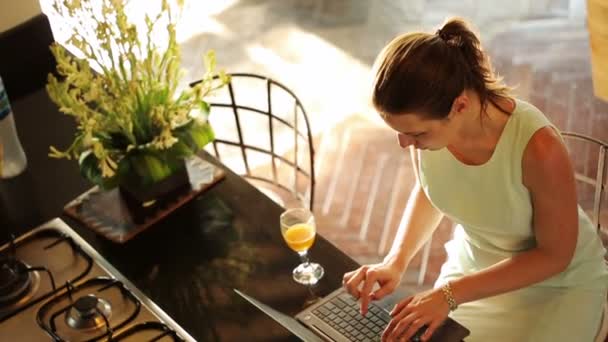 Zakenvrouw bezig met laptop in de keuken — Stockvideo