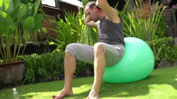 Человек делает приседания на фитнес-мяч — стоковое видео
