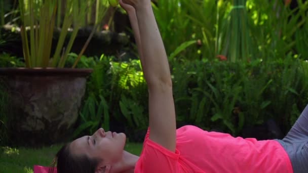 Frau trainiert mit Kurzhanteln im Garten — Stockvideo