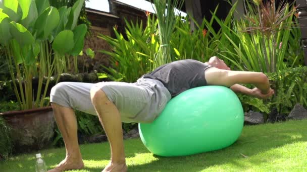 Hombre estirándose en la pelota de fitness — Vídeo de stock