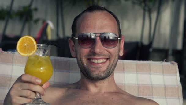 Чоловік п'є коктейль на сонячному ліжку — стокове відео