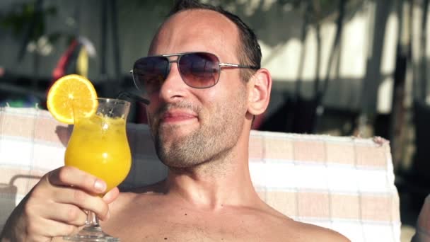 Man drinking cocktail on sunbed — Stock Video