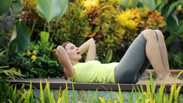 Woman doing sit-ups exercise in garden — Stock Video