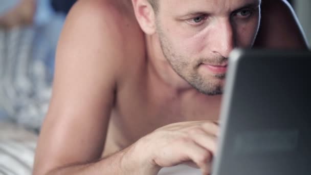 Man met laptop liggend op bed — Stockvideo