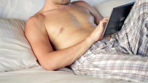 Man met Tablet PC liggend op bed — Stockvideo