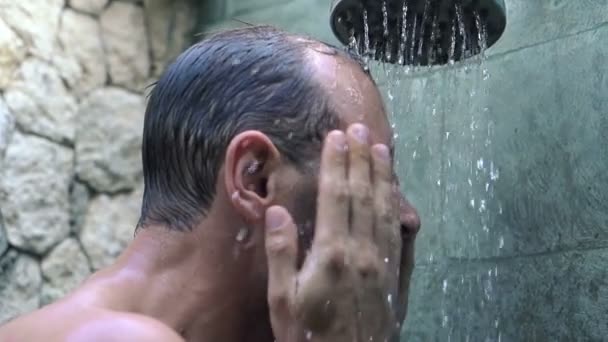 Man wassen gezicht onder douche — Stockvideo