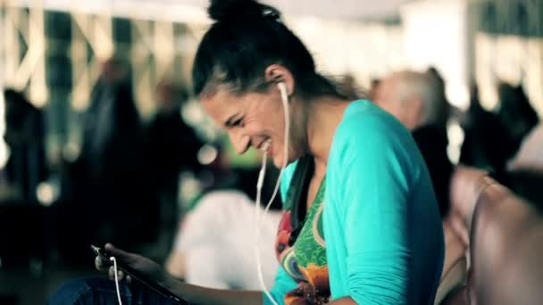 Mujer joven viendo película divertida en la tableta en el aeropuerto — Vídeos de Stock