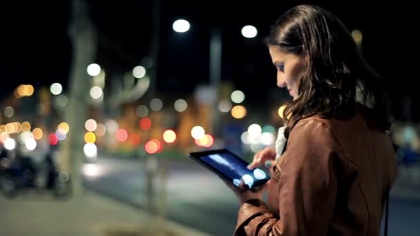 Mujer viendo fotos en la tableta tarde en la noche en la ciudad — Vídeos de Stock