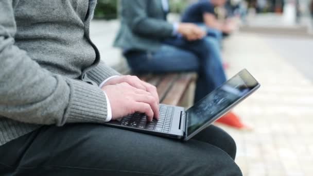 Male hands typing on laptop computer in the city — Stock Video