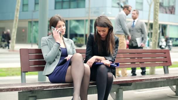 Empresárias conversando no celular no banco da cidade — Vídeo de Stock