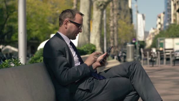 Jonge zakenman werken op de tablet pc in de stad — Stockvideo
