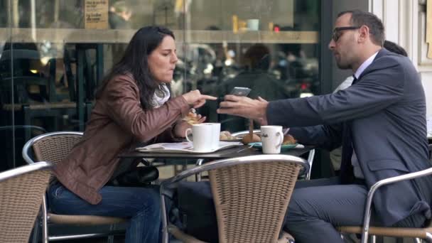 Casal jovem olhando para algo no smartphone durante o almoço no café — Vídeo de Stock