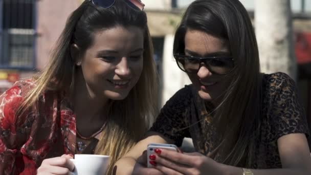 Freundinnen mit Smartphone sitzen im Stadtcafé — Stockvideo