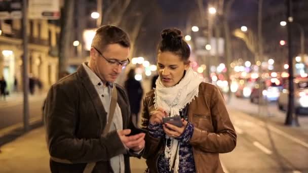 Pareja usando el teléfono celular por la noche en la calle — Vídeo de stock