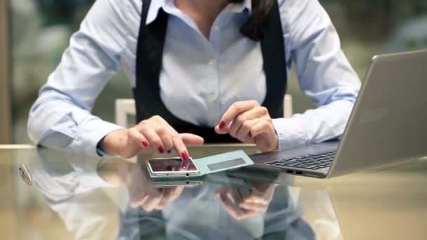 Mujer de negocios calculando algo en el teléfono inteligente junto al escritorio en la oficina — Vídeos de Stock
