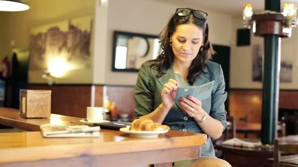 Mujer de negocios con teléfono inteligente moderno sentado junto al mostrador en el bar — Vídeos de Stock