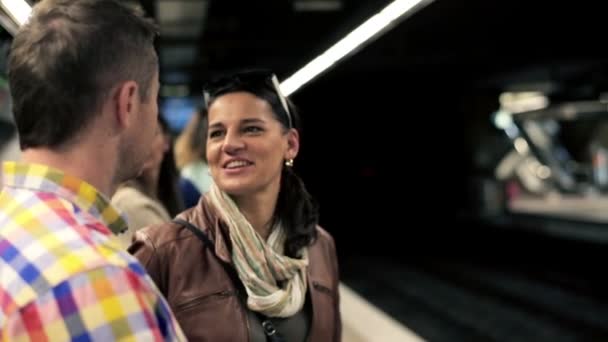 Счастливая молодая пара разговаривает во время ожидания на станции метро — стоковое видео