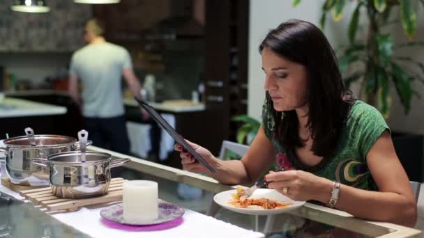 Mujer comiendo la cena, navegar por la web en la tableta junto a la mesa en casa — Vídeo de stock