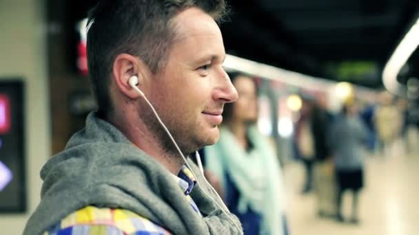 Joven feliz escuchar la música en la estación de metro — Vídeo de stock