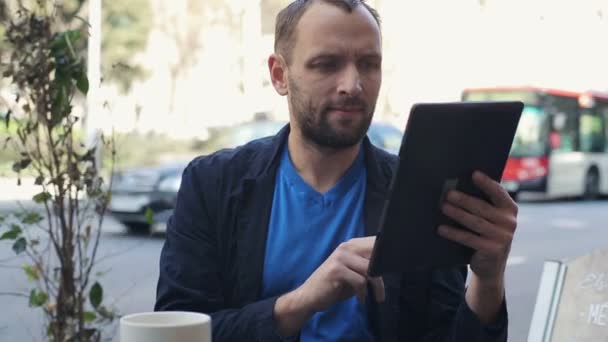 Ung man med Tablet PC-datorn sitter i café — Stockvideo