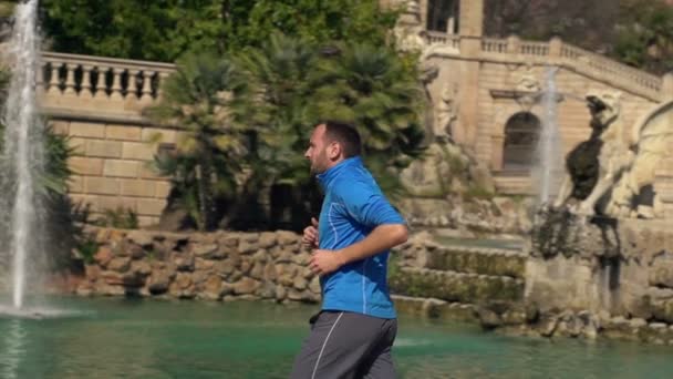 Мужчина бегает у фонтана в парке — стоковое видео
