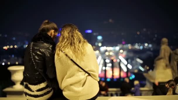 Glückliche Freundinnen sitzen nachts auf einem Hügel mit Blick auf Barcelona — Stockvideo