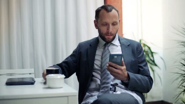 Affärsman dricka kaffe och textning på smartphone — Stockvideo