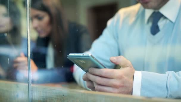 Бизнесмен пишет смс на смартфоне у стойки в кафе — стоковое видео
