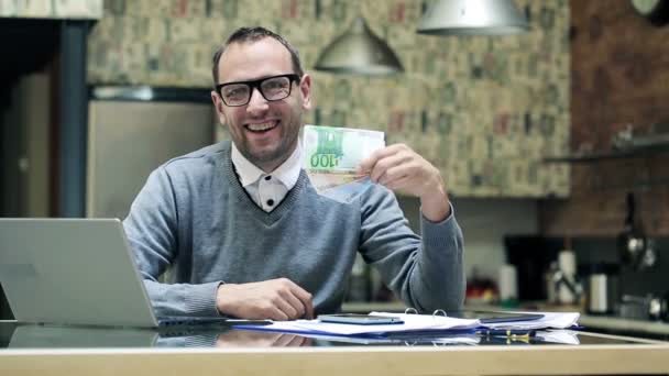 Happy young businessman holding, shaking euro bills, money by the desk — Stock Video