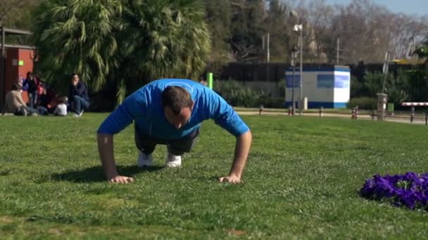 Junger Mann macht Liegestütze im Park — Stockvideo