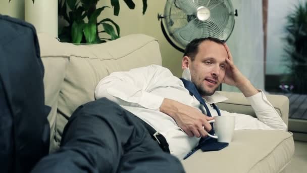 Επιχειρηματίας, πίνοντας τσάι και να χαλαρώσετε στον καναπέ στο σπίτι — Αρχείο Βίντεο