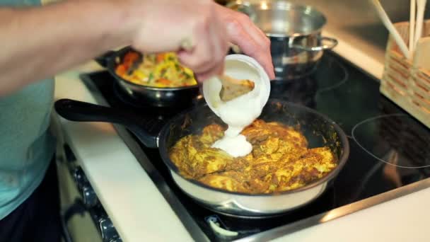 Man adding sour cream to frying meal — Stock Video