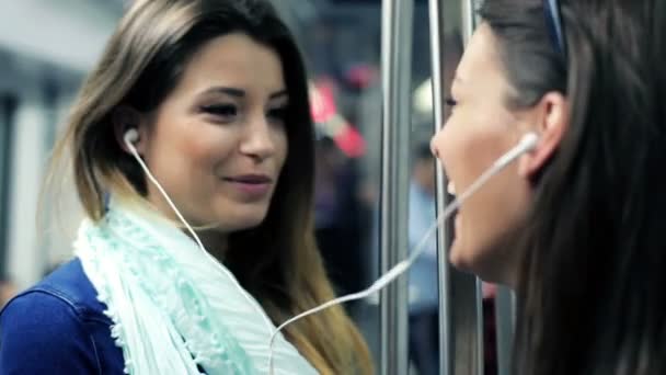 Happy girlfriends listen to music and singing while ride metro train — Stock Video