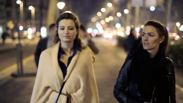 Two girlfriends walking and talking in city at night — Stock Video