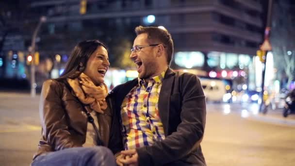 Feliz, riéndose pareja joven por la calle de la ciudad por la noche — Vídeos de Stock