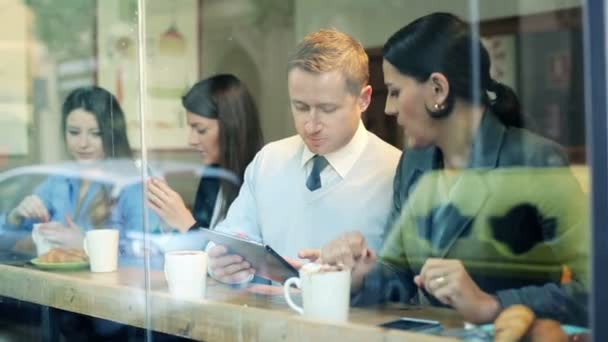 Gente de negocios con tabletas y teléfonos inteligentes charlando en la cafetería — Vídeo de stock