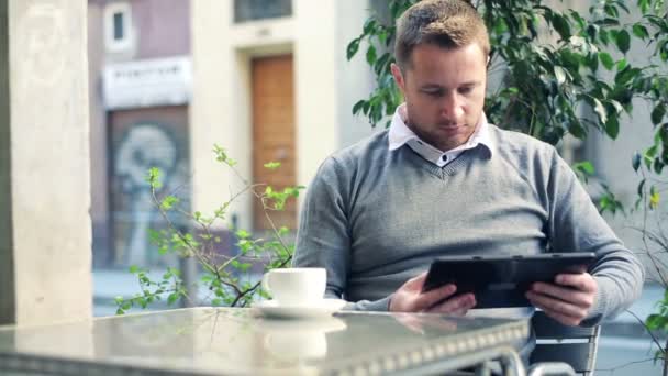 Jonge man aan het werk op de tablet pc in openlucht café — Stockvideo