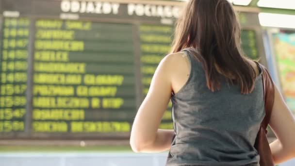 Jovem mulher olhando para informações de tela na estação — Vídeo de Stock