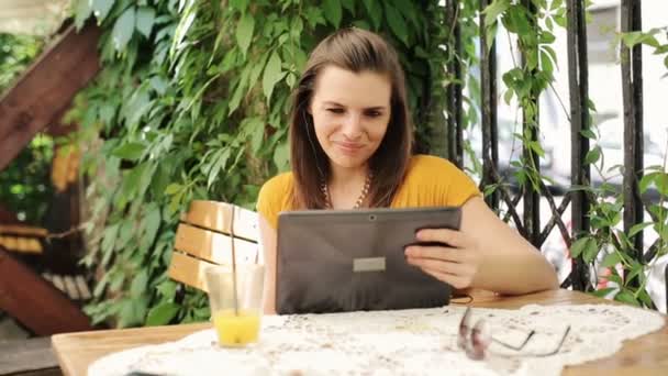 Женщина смотрит смешное кино на планшетном компьютере в кафе — стоковое видео