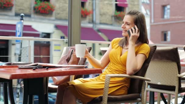 Элегантная женщина разговаривает по мобильному телефону, пьет кофе в ресторане — стоковое видео