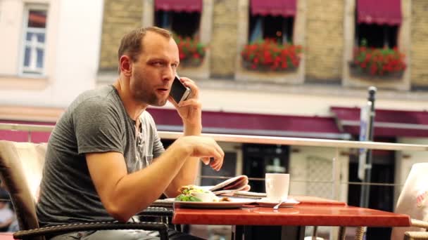 Jonge man praten op mobiel tijdens de lunch in restaurant — Stockvideo