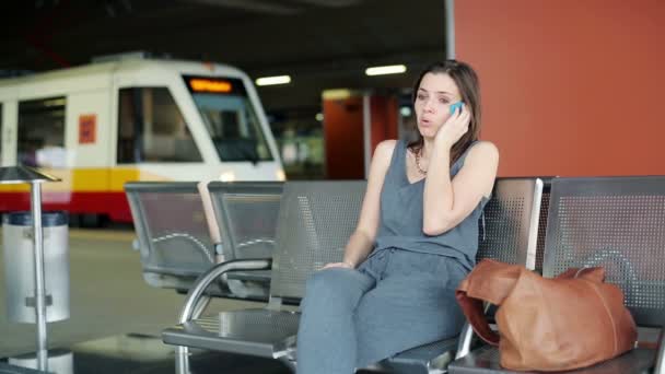 Angry, late woman talking on cellphone at train station — Stock Video