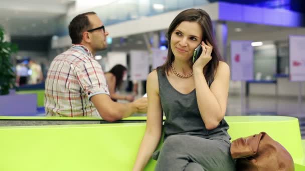 Женщина разговаривает по мобильному телефону на переполненном вокзале — стоковое видео
