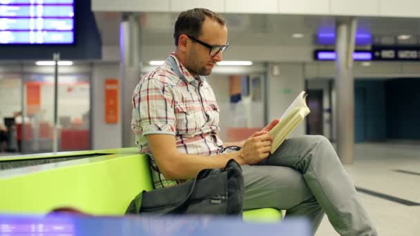 Joven leyendo libro, esperando en la estación de tren — Vídeos de Stock