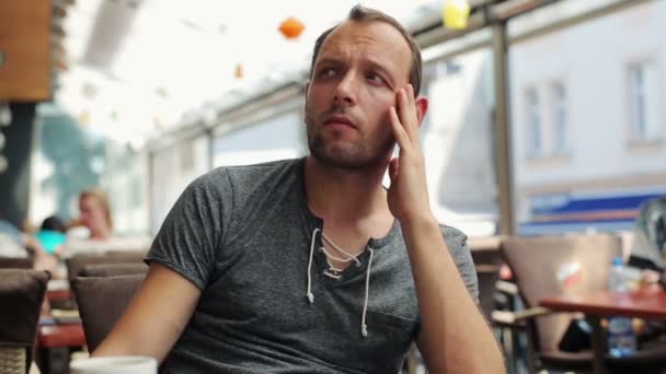 Portret van jonge verdrietig man zittend in restaurant — Stockvideo