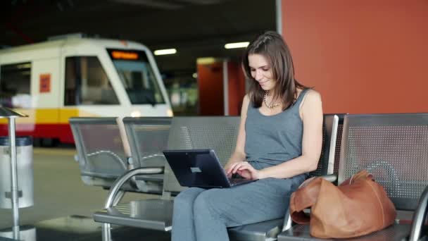 Young pretty woman with laptop computer at train station — Stock Video