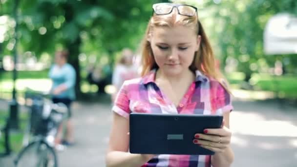 Tonårsflicka med tablett i park — Stockvideo